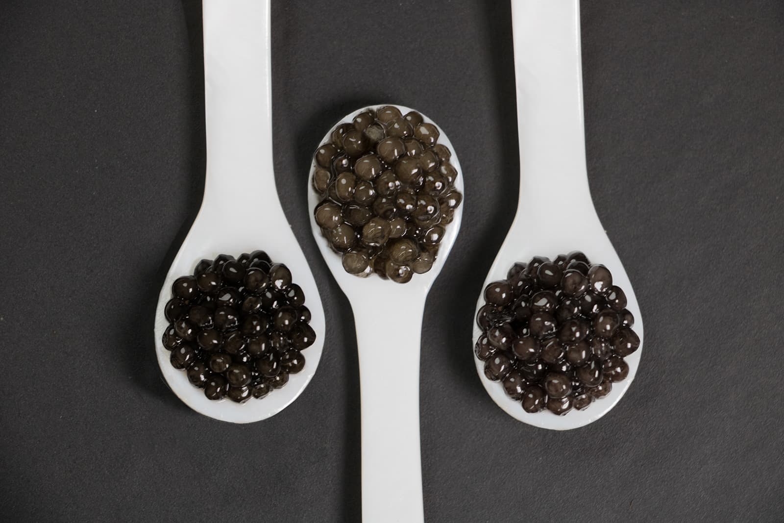 Trois cuillères blanches garnies de différents caviars