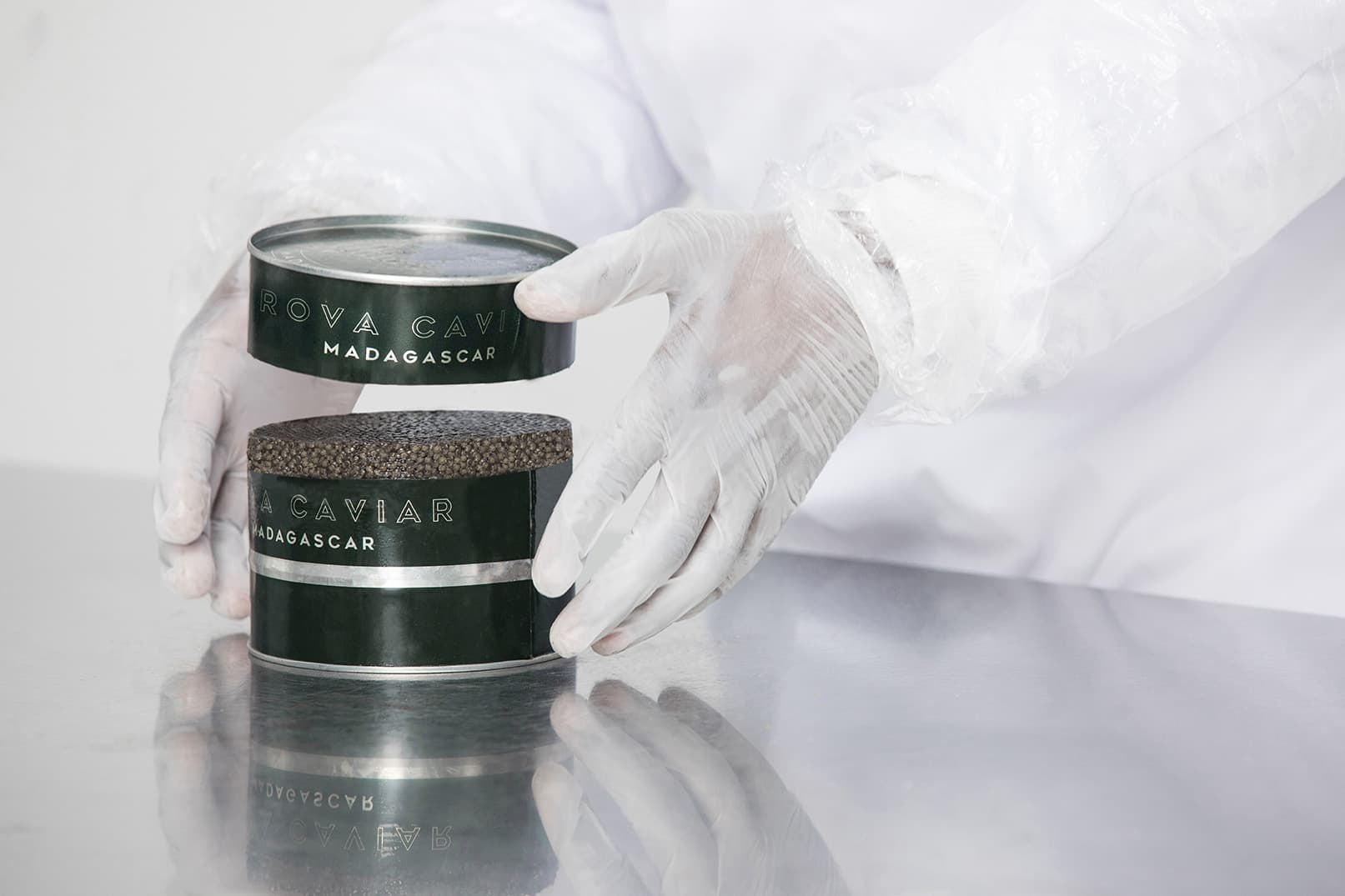 Mains gantées refermant deux boîtes de caviar Rova