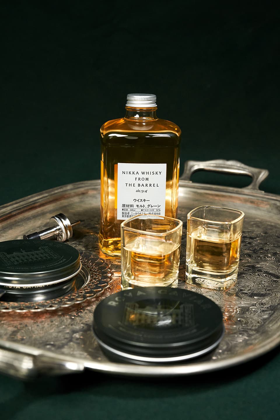Bouteille de whisky, verres et boîtes de caviar sur un plateau en argent