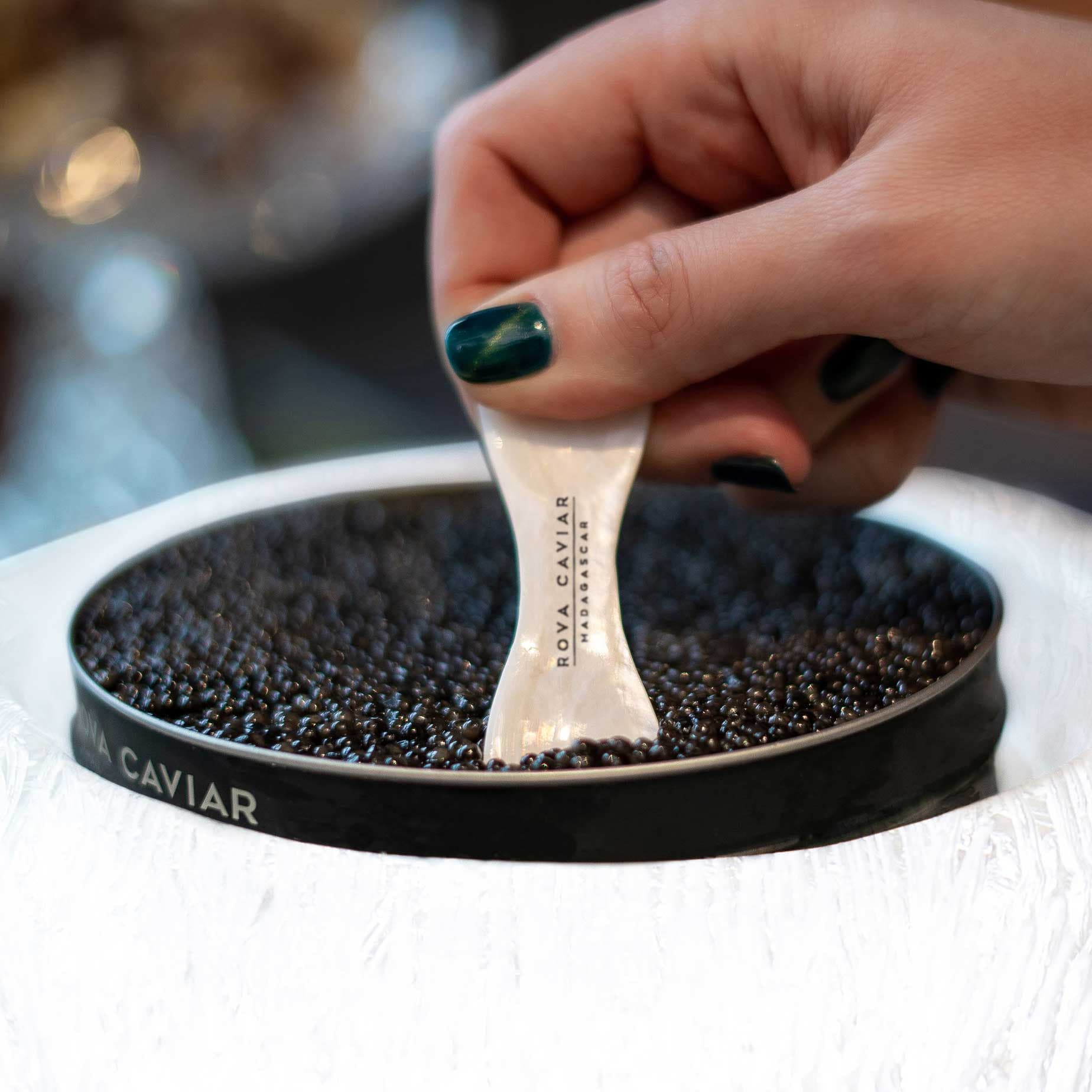 Main se servant du caviar Rova à l'aide d'une cuillère en nacre
