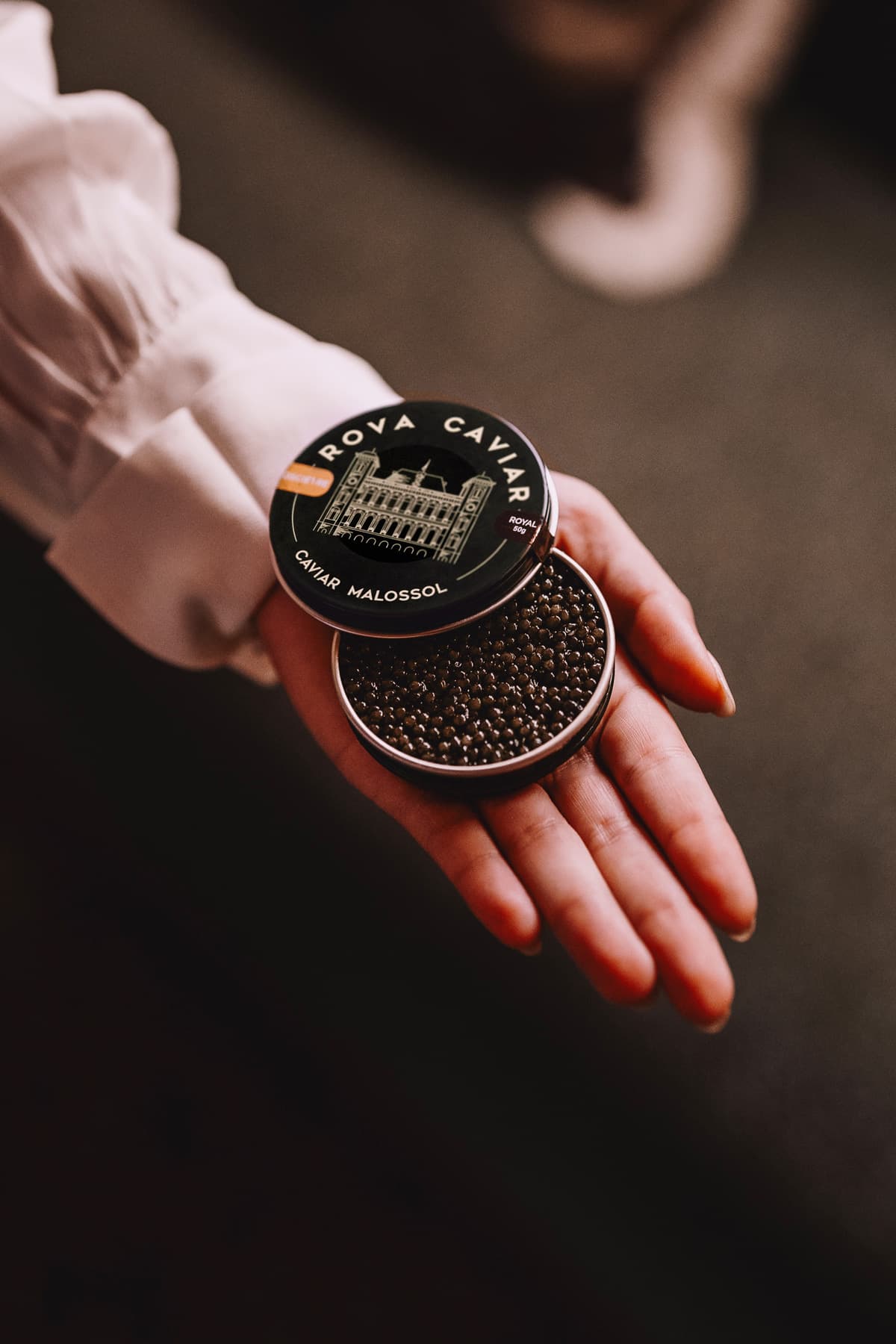 Boîte de caviar ouverte présentée dans la paume d’une main