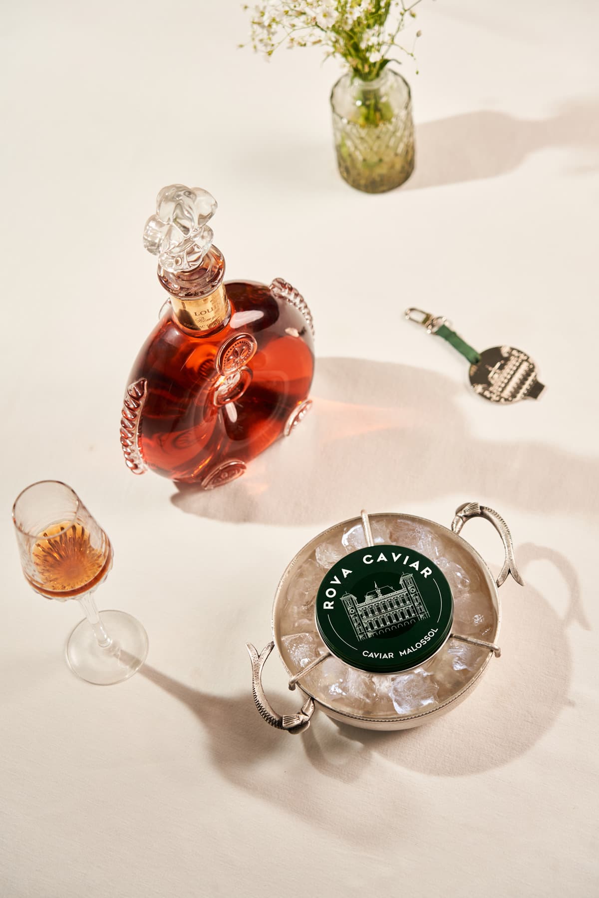 Carafe de cognac, verre et boîte de caviar Rova Caviar sur une table claire